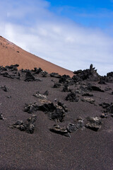 Lanzarote volcanic landscape with black lava sand and red mountain