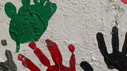 Colorful handprints painted on a textured white wall green