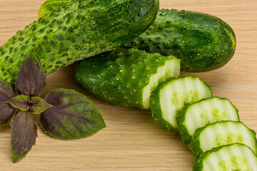 Fresh cucumbers sliced with purple basil on a wooden board
