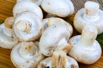 Fresh white button mushrooms pile on wooden surface