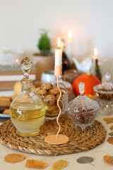 Lit candles, cookies, chocolate, nuts, tea, wine, pumpkins, books, reading glasses and autumn leaves on the table. Autumnal hygge at home. Selective focus.