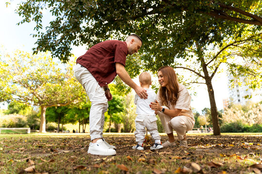 Ukrainian family in park helping baby walking