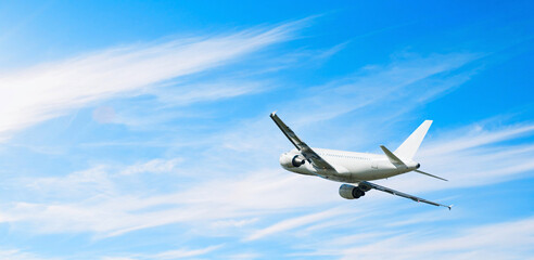 White passenger airplane flying in the sweeping blue sky, air travel background with airplane in the flight