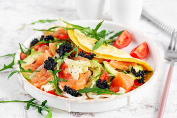 Healthy breakfast. Quesadilla with omelette, salmon, avocado, black caviar and tomatoes. Keto, ketogenic lunch.