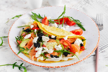 Healthy breakfast. Quesadilla with omelette, salmon, avocado, feta cheese, black caviar and tomatoes. Keto, ketogenic lunch