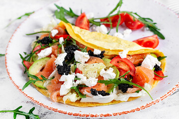 Healthy breakfast. Quesadilla with omelette, salmon, avocado, feta cheese, black caviar and tomatoes. Keto, ketogenic lunch