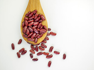 Red bean seeds on a wooden spoon on a white background