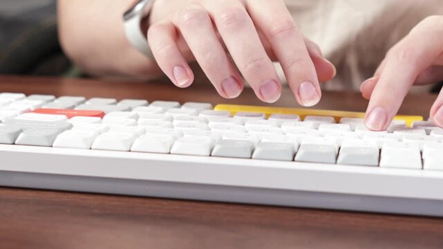 Engaged hands quickly typing on a contemporary white computer keyboard with yellow and red accent keys, symbolizing digital productivity, data entry, and efficient communication