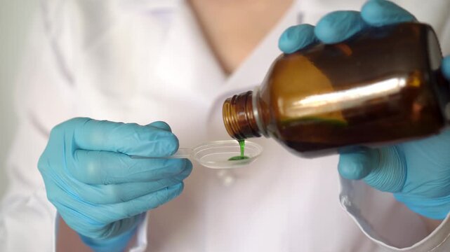 The doctor pours the medicine into a spoon