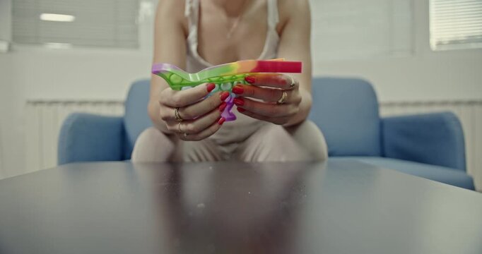 A woman engages with a vibrant, dinosaur-shaped Pop-It fidget toy, creating satisfying popping sounds. This video highlights the tactile and auditory experience of anti-stress play.