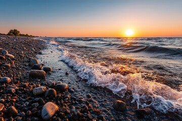 Obraz premium Golden Sunset over Rocky Beach with Gentle Waves and Bright Sunlight