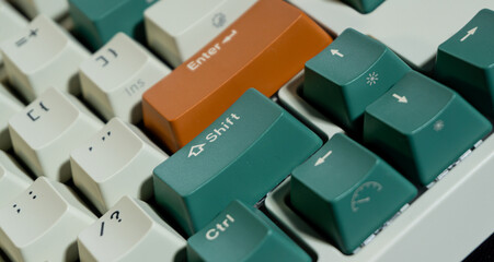 Macro photo of orange Enter and green Shift keys on a mechanical keyboard, focus centered on key legends, blurred surroundings enhance contrast and tone.