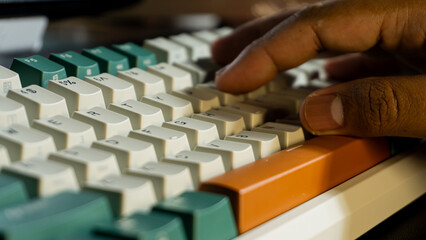 Hand typing on mechanical keyboard with orange Enter key, focus on middle keys and thumb area, background smoothly blurred for soft professional tone.