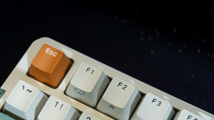 Minimalist photo of orange Escape key on a retro mechanical keyboard, clear focus on ESC and nearby F-keys, dark blurred background adds contrast and mood.