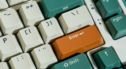 Close-up of a mechanical keyboard showing an orange Enter key among white and green keycaps, sharp focus on Enter area with slight background blur for depth.