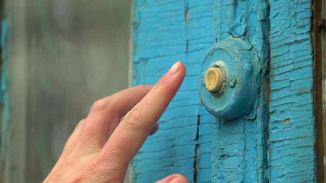 Woman pressing the doorbell button on the old blue door 02