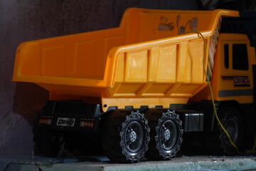 Large yellow plastic toy dump truck on a dark background.