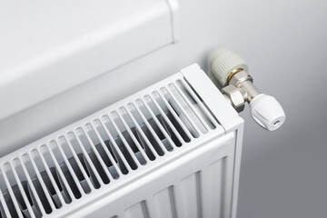 A steel panel heating radiator is placed under the windowsill on a white