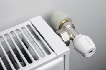 A steel panel heating radiator is placed under the windowsill on a white