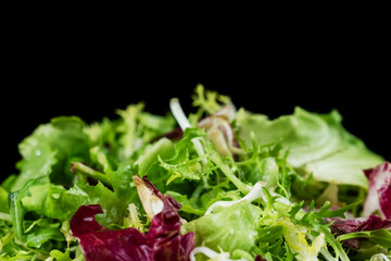 A mixture of healthy greens in a plate on a black background. Diet food