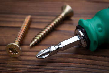 screwdriver and screws on wooden background close up