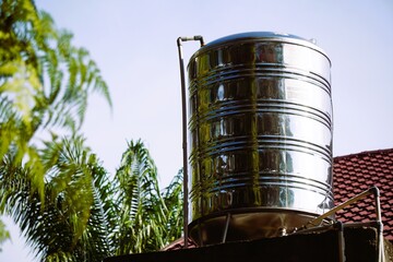 Shiny Stainless Steel Water Tank on Rooftop with Lush Greenery.