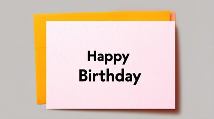 Card with the words Happy Birthday written on it. The card is yellow and pink and is sitting on top of another card