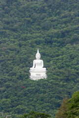 Serene Buddha atop Mountain: A majestic, pristine white statue of the Buddha finds serenity on a lush, forested mountain, creating a tranquil panorama of spiritual significance.