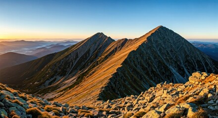 Sunrise bathes rugged mountains with golden light, a panorama of peaks and valleys
