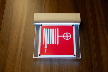 Illuminated sign with fire cabinet symbol. Sign depicting fire hydrant indicates location of water hose connection. Safety concept for public spaces thanks to fire protection systems
