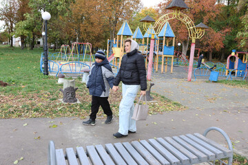 A woman and her son are walking home after a pleasant walk in the autumn park.