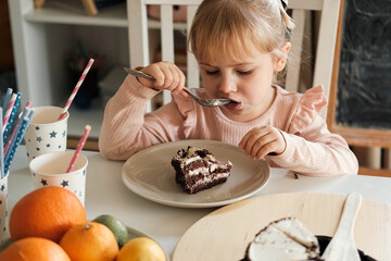Children Eating Birthday Cake Slice on a Birthday Party at Home. Siblings, girls and a boy together...