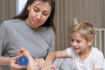 Mother using a spiky massage ball for son to relieve muscle tension, aid recovery after training....