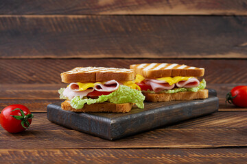 Delicious sandwich with ham, cheese, tomato and lettuce on toasted bread. Perfect lunch or snack idea