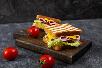 Delicious sandwich with ham, cheese, tomato and lettuce on toasted bread. Perfect lunch or snack idea