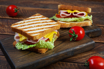 Delicious sandwich with ham, cheese, tomato and lettuce on toasted bread. Perfect lunch or snack idea