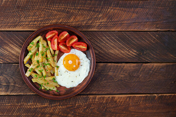 Homemade morning breakfast with fried egg, crispy potato and fresh tomatoes