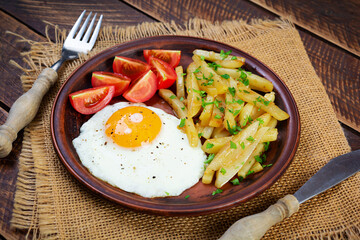 Homemade morning breakfast with fried egg, crispy potato and fresh tomatoes