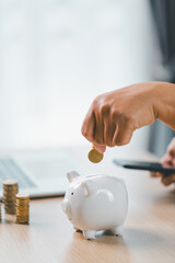 Concept of saving money and investment planning. A businesswoman drops coin into white piggy bank...