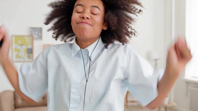 Happy woman dancing with headphones indoors, joyful expression enjoying music in bright living room, positive energy lifestyle concept, freedom happiness feeling rhythm sound emotion, modern home rela