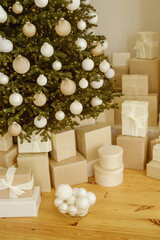 Gift boxes under a contemporary Christmas tree in a home, adorned with holiday Xmas ornaments