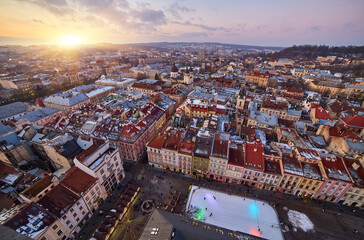 Fototapeta premium Aerial view of a historic European city with snowy rooftops at sunset.