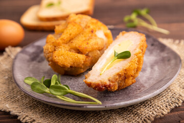 Chicken Schnitzel on gray plate with microgreen on brown wooden background and linen textile. side view, selective focus