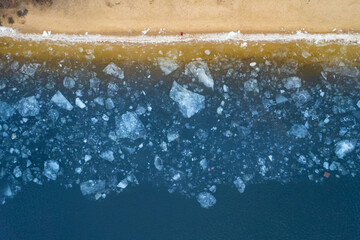 Aerial top down view of a frozen seashore with broken ice.