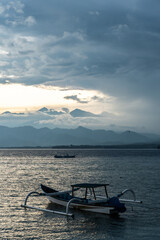 Jukung boat navigating sea mountains cloudy sky