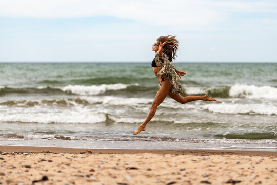 A carefree woman joyfully running on the beach, capturing the essence of summer freedom and vitality