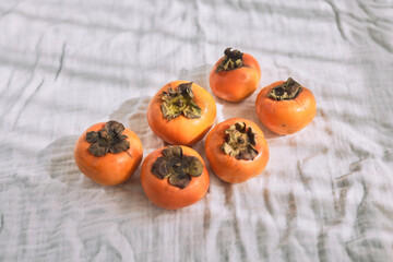 Persimmons on soft white fabric in natural light