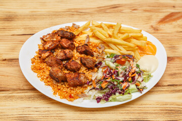Assiette brochette d'agneau servie avec blé, frites et salade – restauration rapide turque halal