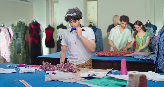 Indian young adult gen z man wear tape around neck learn new craft course class room. Smart male boy pupil hold pencil do casual fabric pattern look paper on table enjoy day college place	