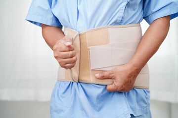 Asian senior wearing elastic support belt can help reduce back pain.